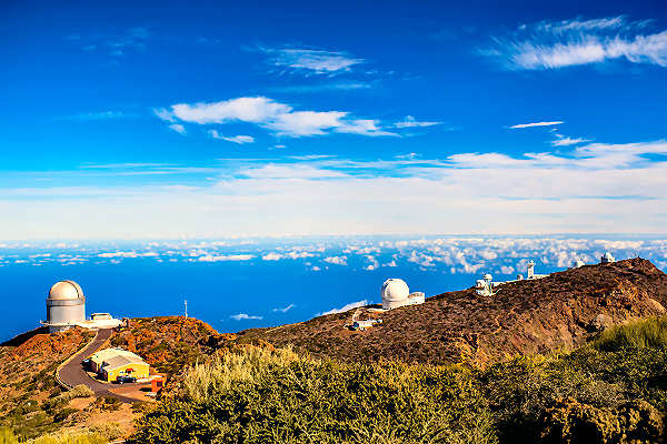La Palma Urlaub – Roque de los Muchachos: Höchster Punkt und Sternenbeobachtung. Aussicht vom Roque de los Muchachos auf La Palma mit Sternenhimmel und Observatorium.