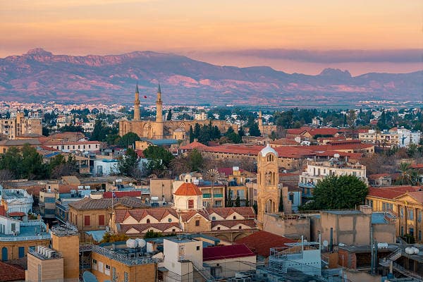 Blick über Nikosia, die Hauptstadt Zyperns, mit historischen Gebäuden, Moscheen und Bergen im Hintergrund bei Sonnenuntergang