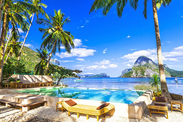 Tropisches Resort mit Pool am Meer auf Palawan, umgeben von Palmen und Kalksteinfelsen auf den Philippinen.