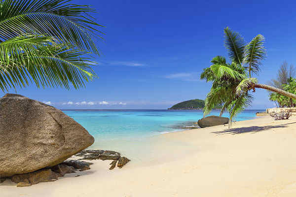 Strand in Khao Lak an der Andamanensee mit Palmen, Felsen und türkisfarbenem Meer